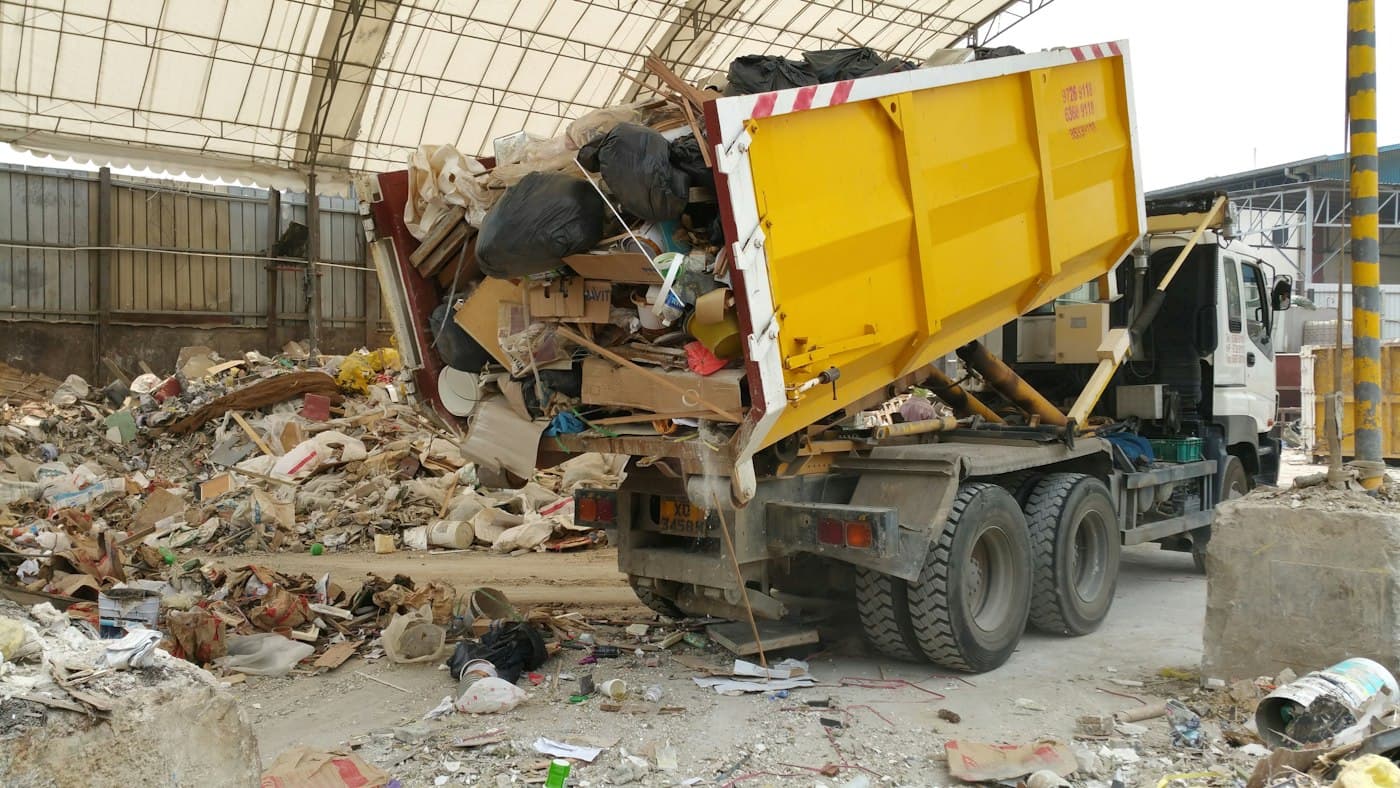 A dump truck unloading a load of discarded household materials at a disposal facility